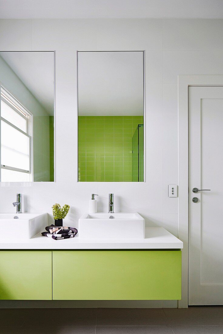 Modernes Badezimmer mit grünem Waschtisch und Fliesenspiegel