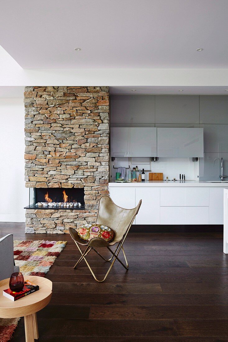 Designerstuhl im offenen Wohnraum mit Kamin und Küche