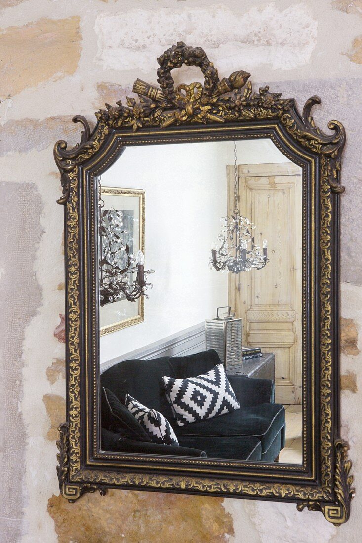 Black velvet sofa reflected in antique wall-mounted mirror