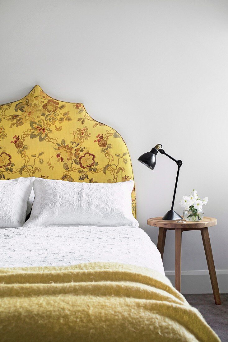 Stool next to the bed with a yellow upholstered headboard