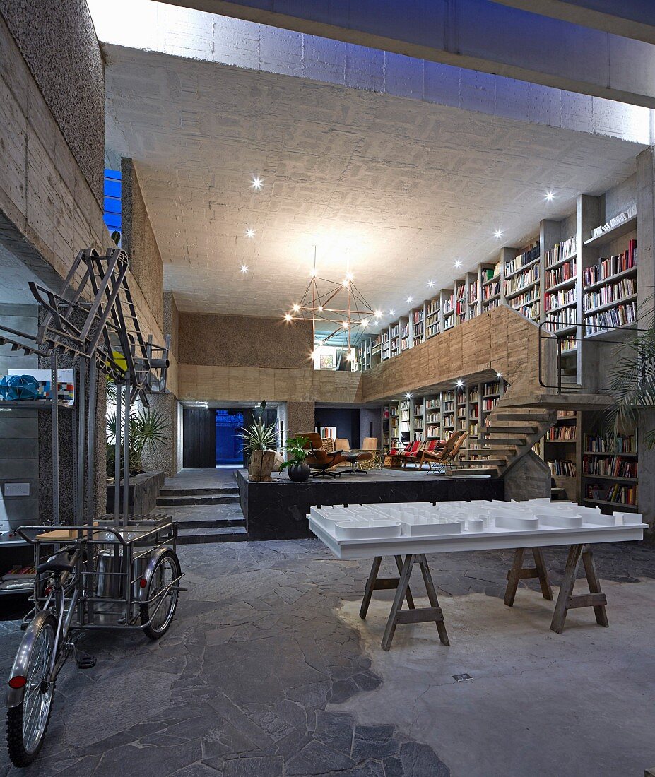 Offener Wohnraum mit Bücherwand in einem Haus aus Beton