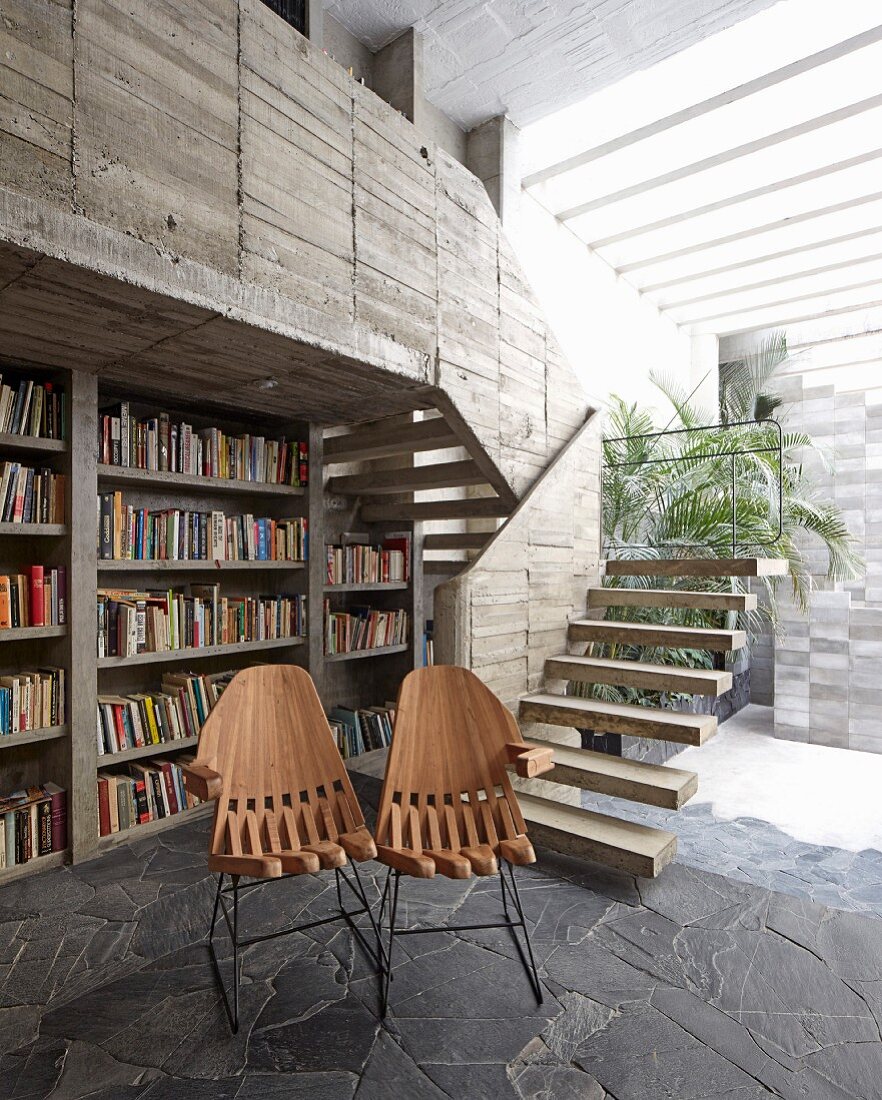 Designerstülhe vor Bücherwand in einem Haus aus Beton