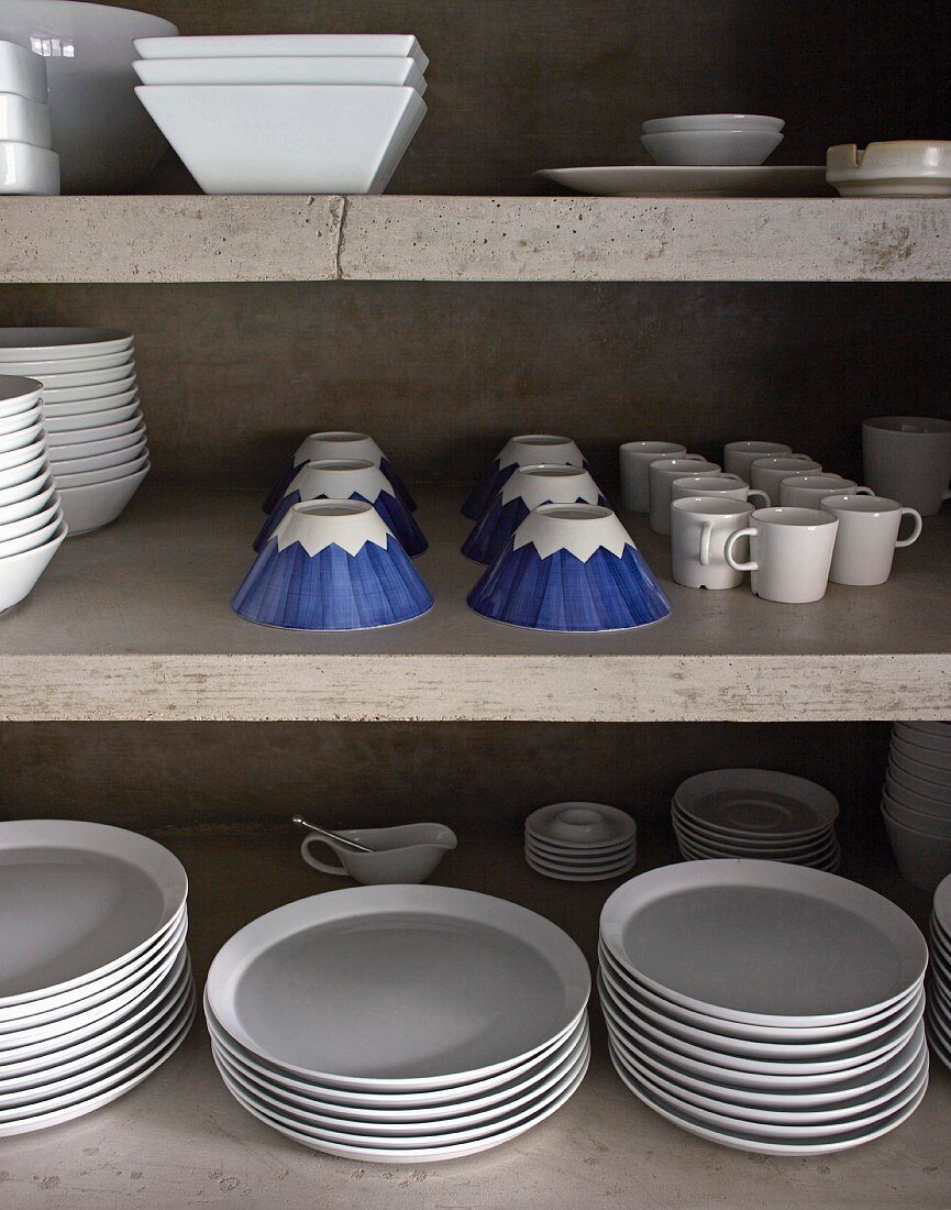 Weißes Geschirr und blau gemusterte Tassen in Beton-Regal
