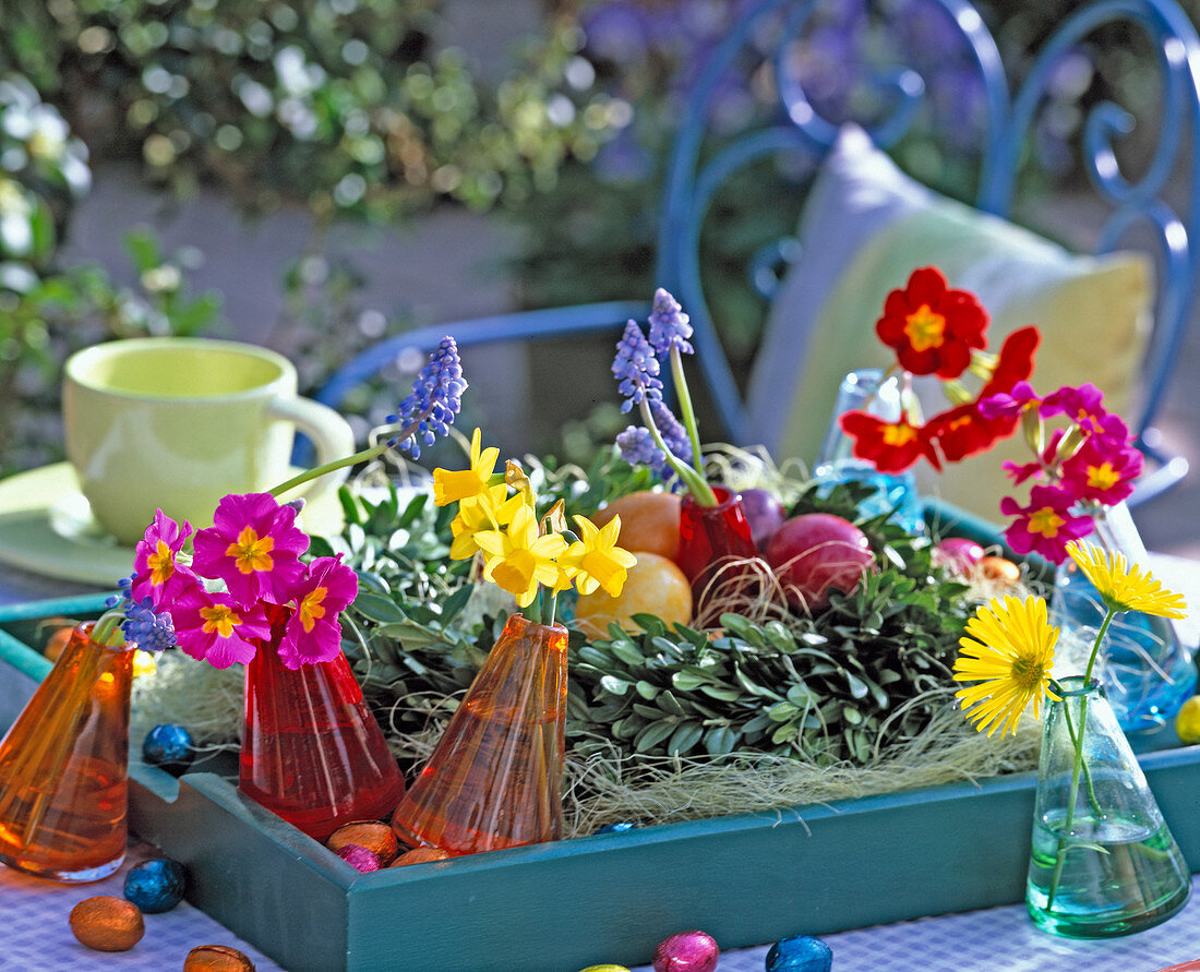 Tablett mit Buchskranz, gekochten Eiern, Vasen mit Blüten