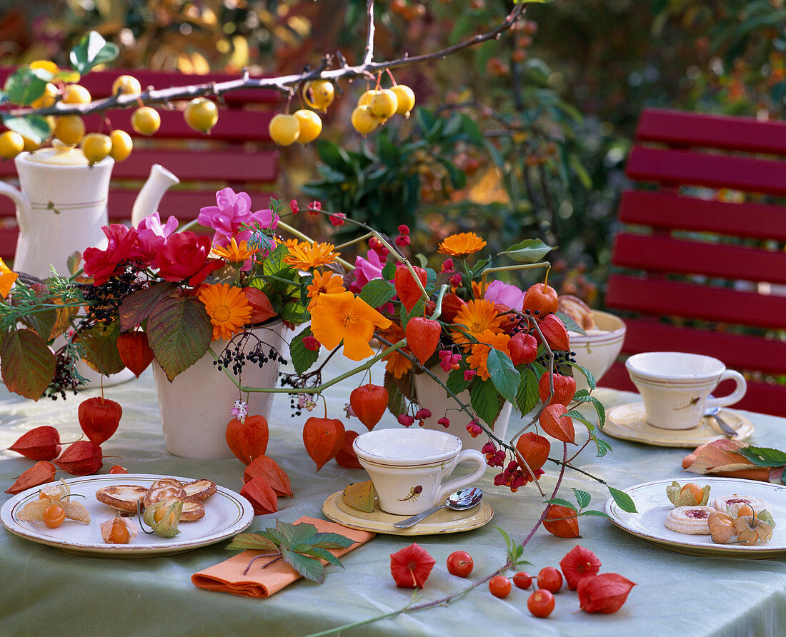 Table decoration made of pink roses, calendula marigolds, physalis lantern flower