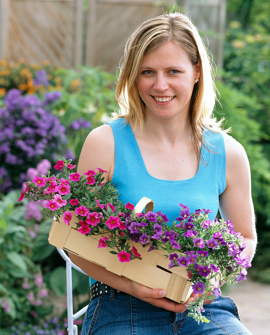 Junge Frau mit Calibrachoa Celebration 'Dark Blue', 'Pink' (Zauberglöckchen)