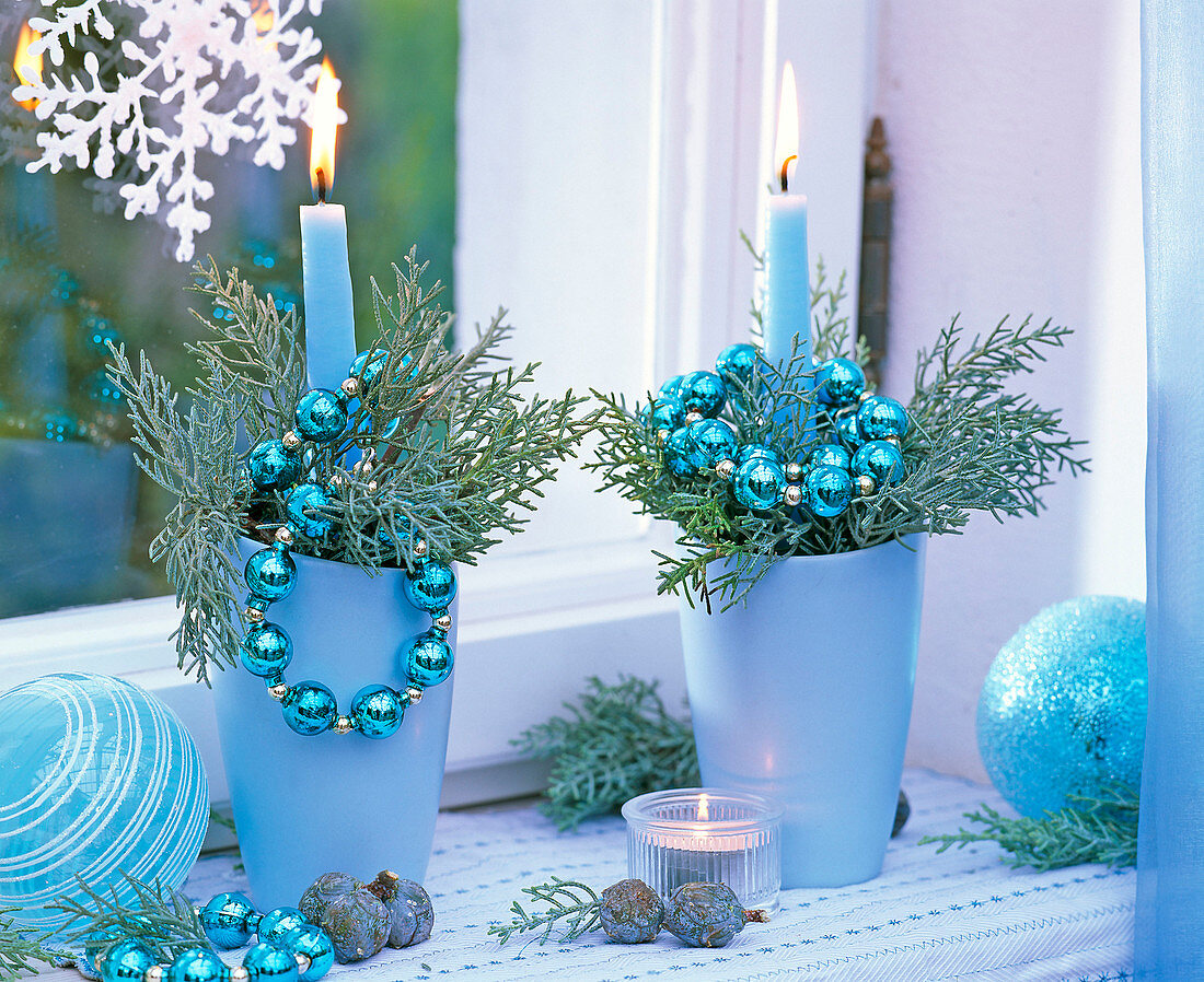 Kerzengestecke mit blauen Kerzen und Vasen mit Juniperus chinensis