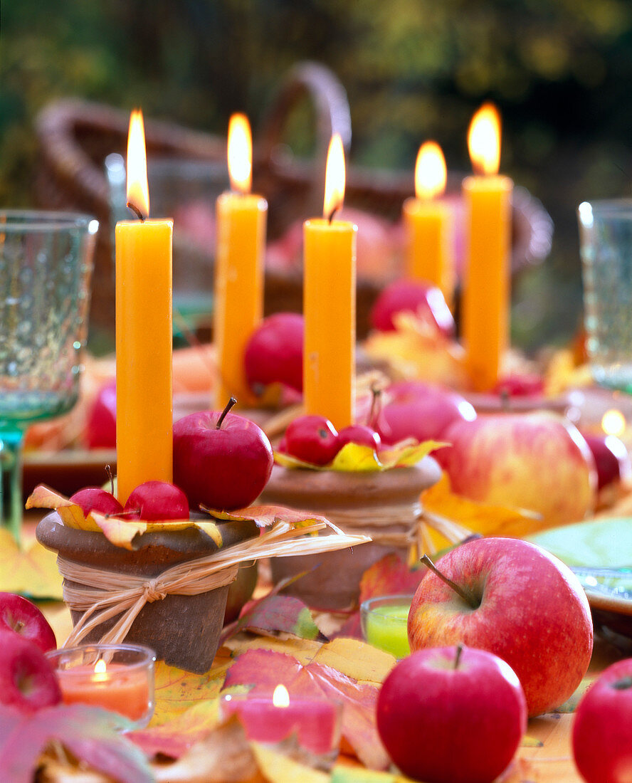 Orange candles in clay pots, decorated with malus