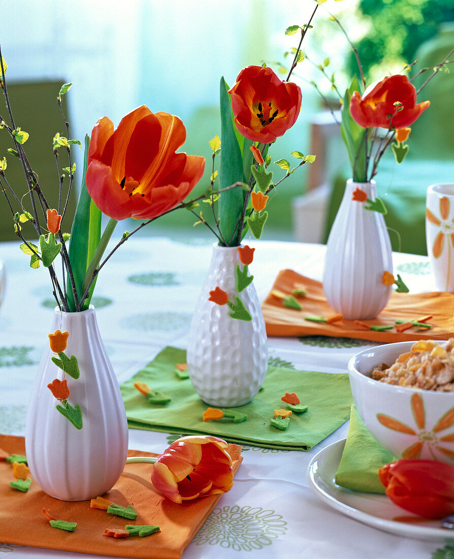 Tulipa (Tulpen, orange - rot), Betula (Birke) in kleinen weißen Vasen