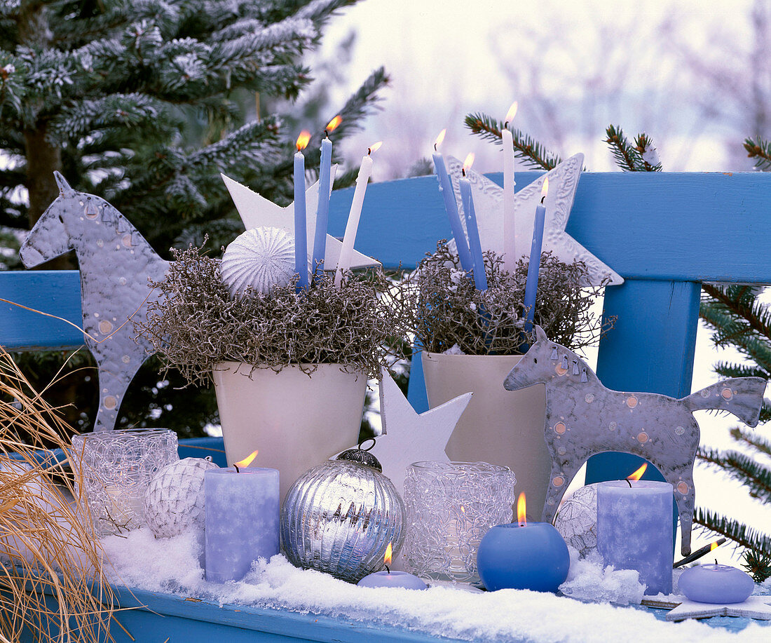 Weihnachtliches Arrangement auf blauer Bank mit blauen und weißen Kerzen