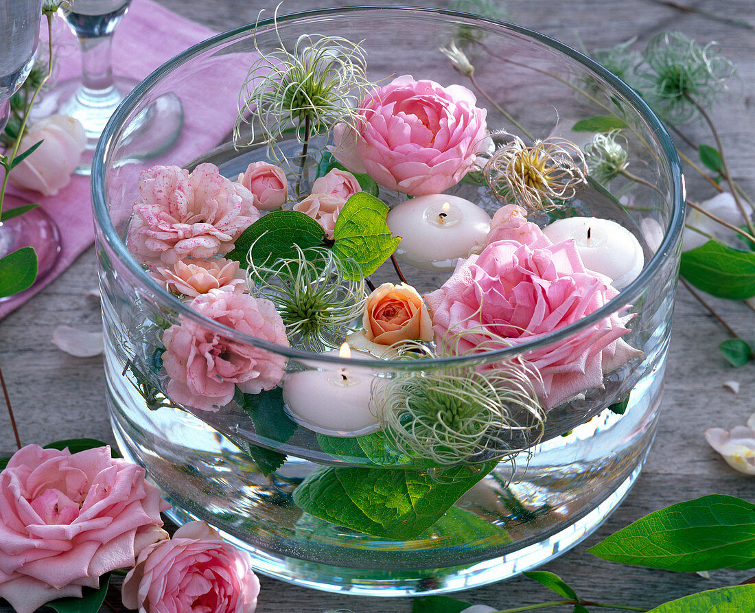 Pink flowers of roses, clematis, white floating candles