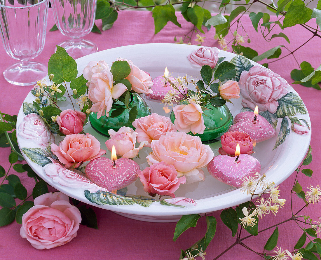 Flowers of pink rose, clematis, heart-shaped floating candles