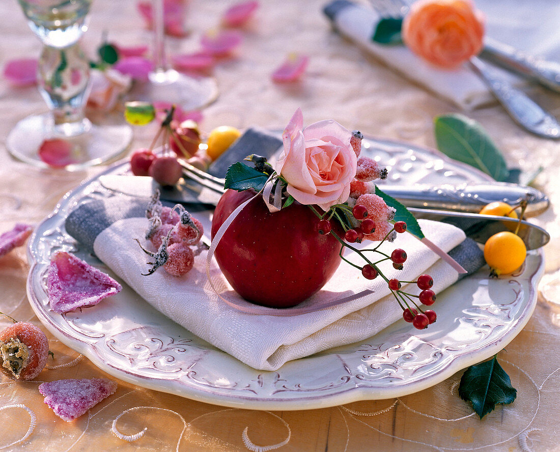 Rosa (Rosen, Hagebutten) und Malus (Äpfeln, Zieräpfeln) auf weißer Serviette