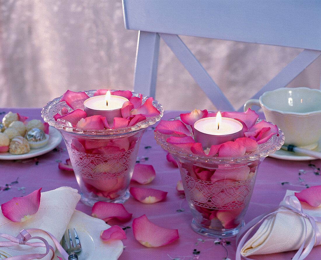Blütenblätter von Rosa (Rosen) in Kerzengläsern mit Teelichtern, Servietten