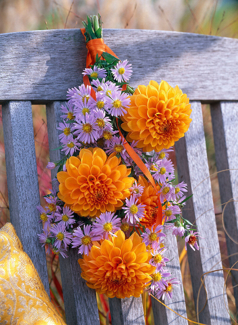 Bouquet of dahlia and aster hanging on wooden chair
