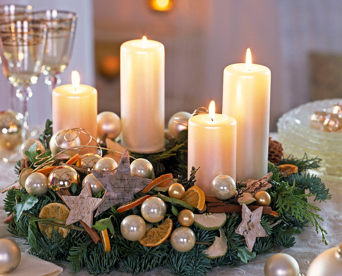 Adventskranz mit weißen Kerzen, Kugeln, Sternen, Orangenscheiben und Zimtstangen