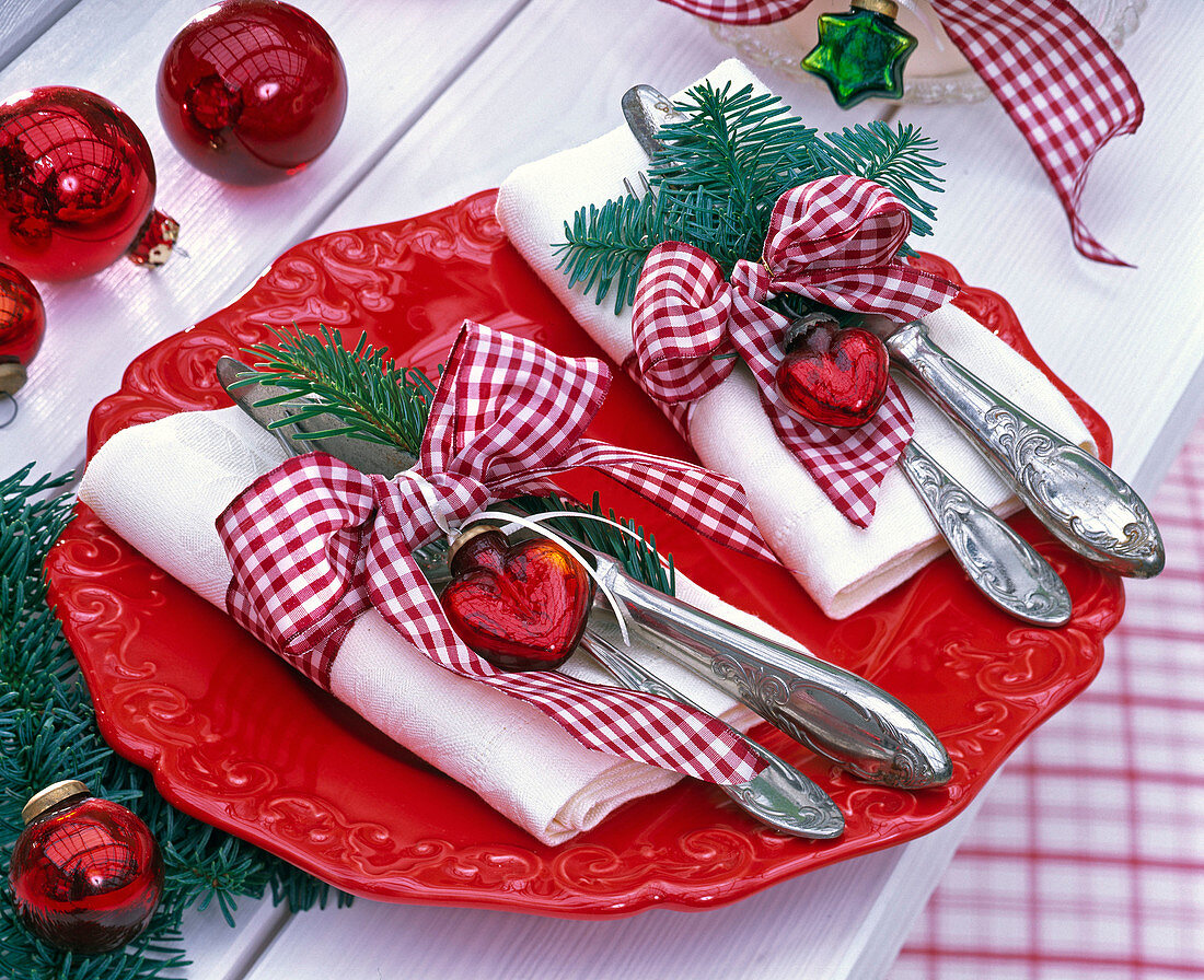 Abies branches on white napkins with red checkered ribbons