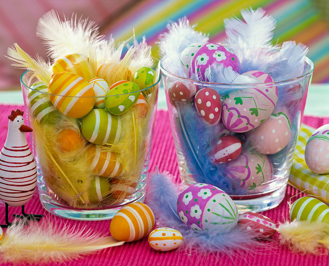 Patterned easter eggs in glass vases with feathers, chicken