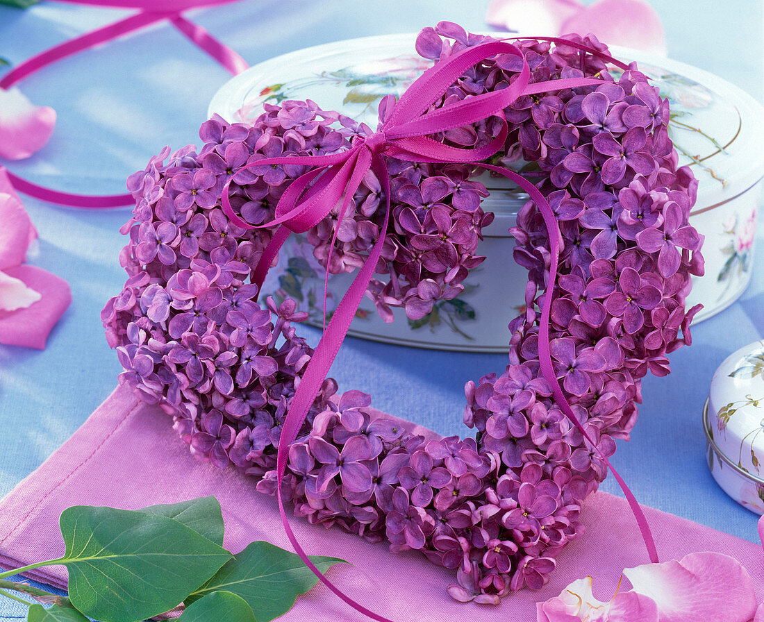 Syringa heart with ribbon leaning against porcelain can, napkin