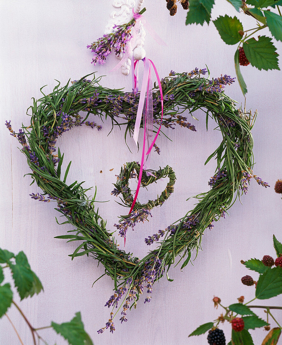 Zwei Kränze in Herzform aus Lavandula (Lavendel) ineinander an der Wand