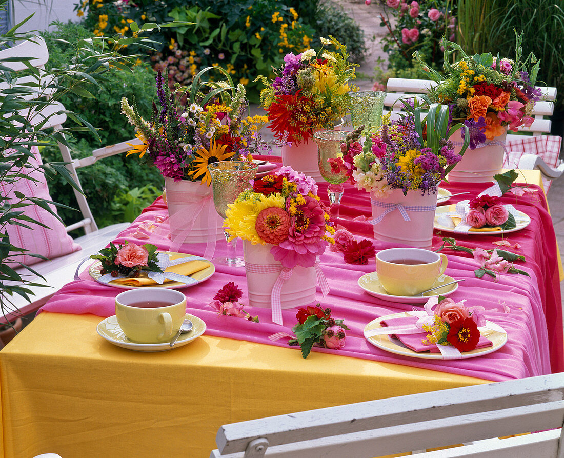 Tischdekoration mit Sträußen aus Zinnia (Zinnien), Solidago (Goldrute)