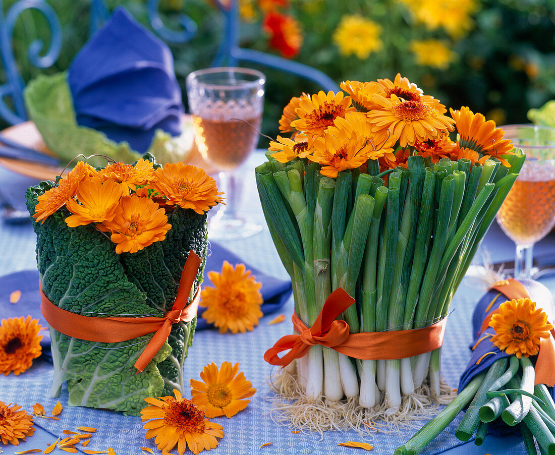 Sträuße aus Calendula (Ringelblumen) in Vasen, die mit Brassica (Wirsing)
