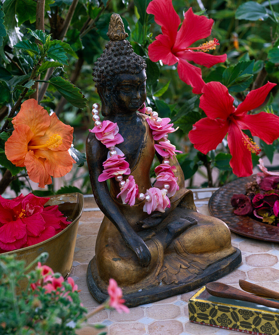 Buddha figure with a threaded chain of pink flower petals