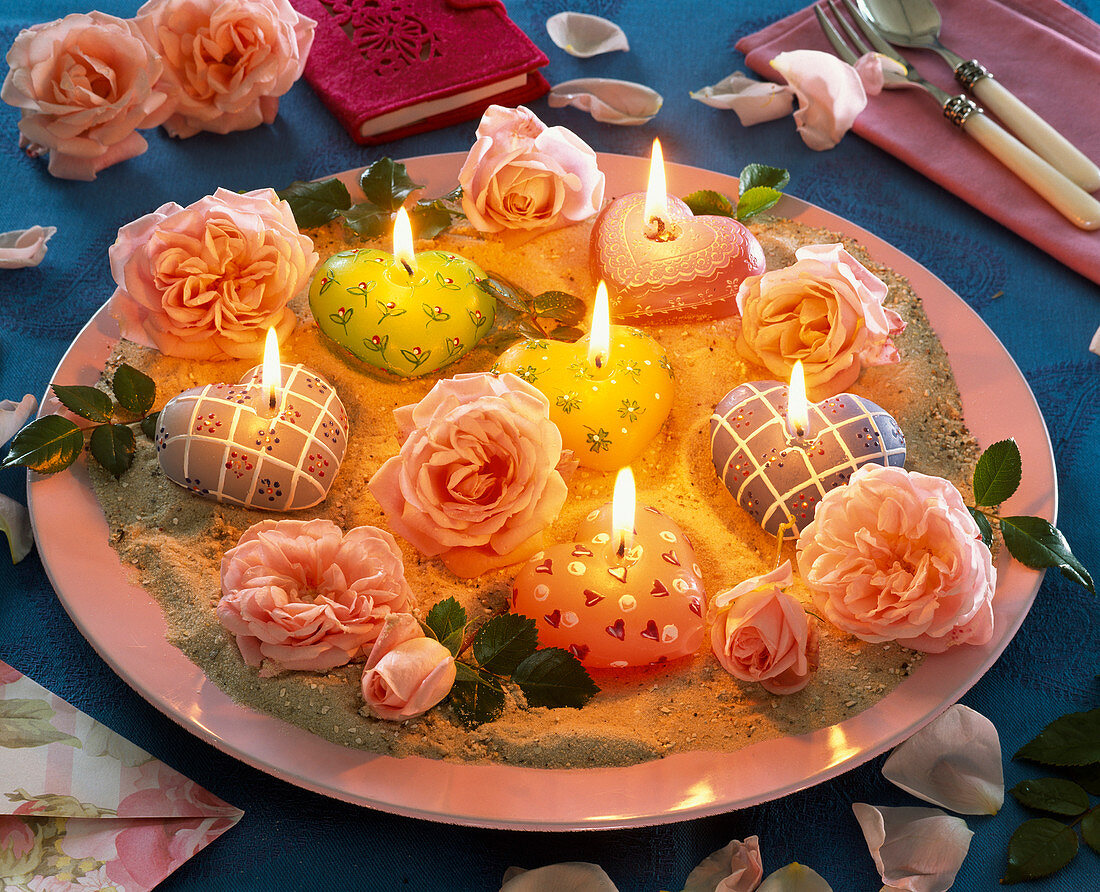 Blüten von Rosa (Rosen), Kerzen in Herz - Form auf rosa