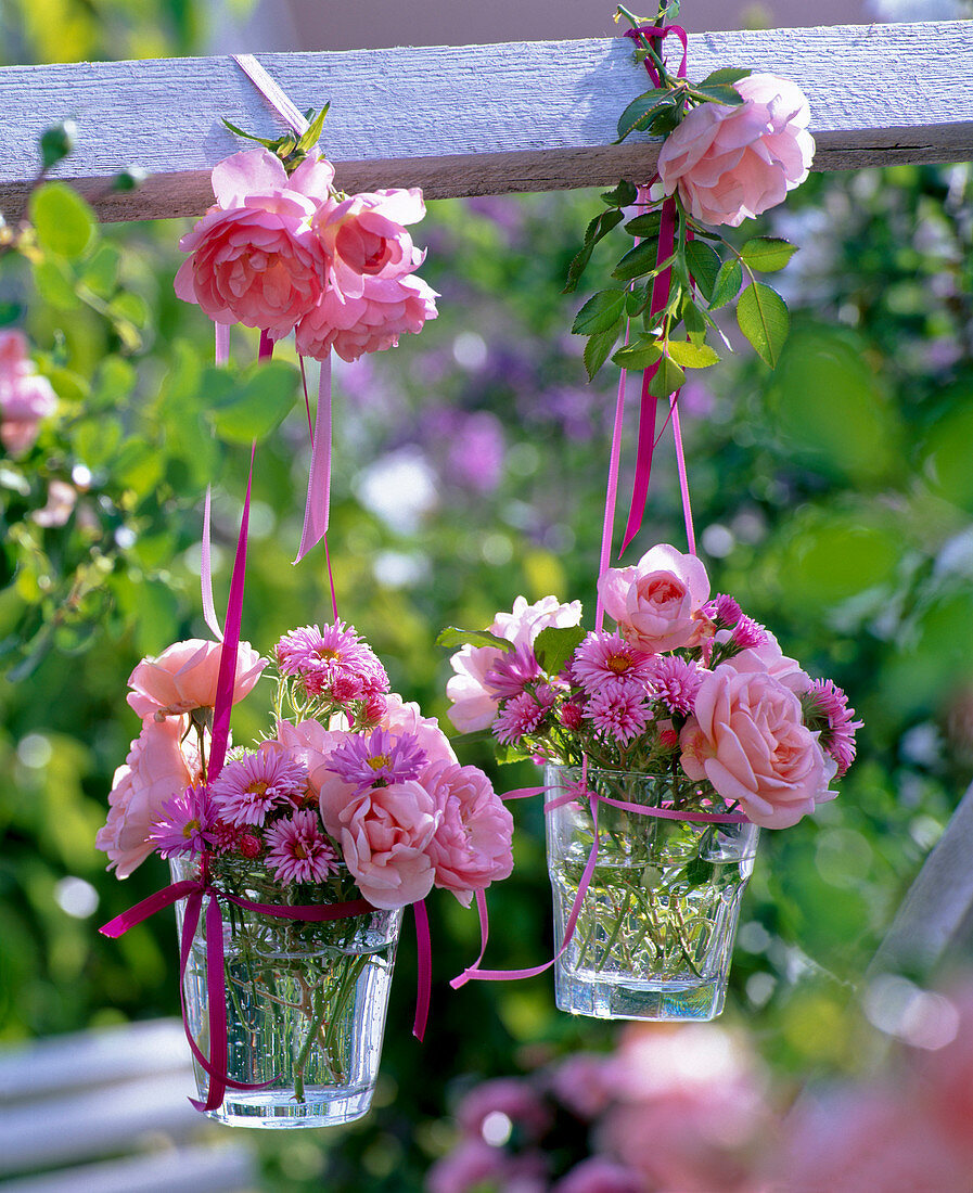 Kleine Sträuße aus Rosa (Rosen) und Aster (Herbstastern) in kleinen Gläsern