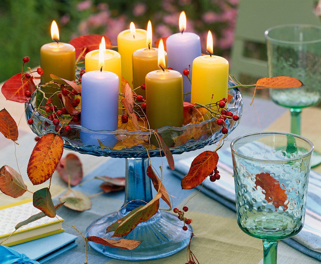 Rosehips, autumn Prunus leaves, candles on glass bowl