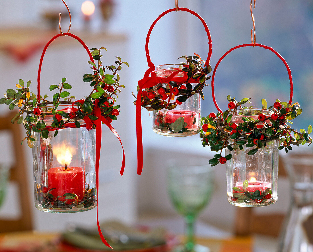 Schraubgläser als hängende Windlichter mit kleinen Kränzen aus Cotoneaster