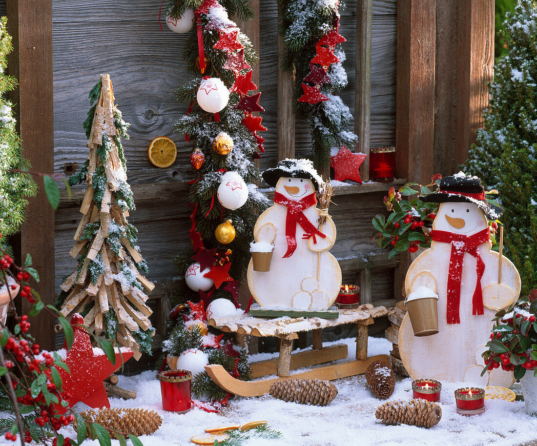 Terrace near Christmas tree made of pieces of wood and branches, snowmen