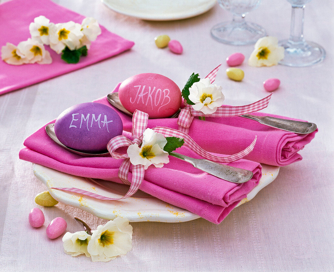 Table decoration with primula on pink folded napkins