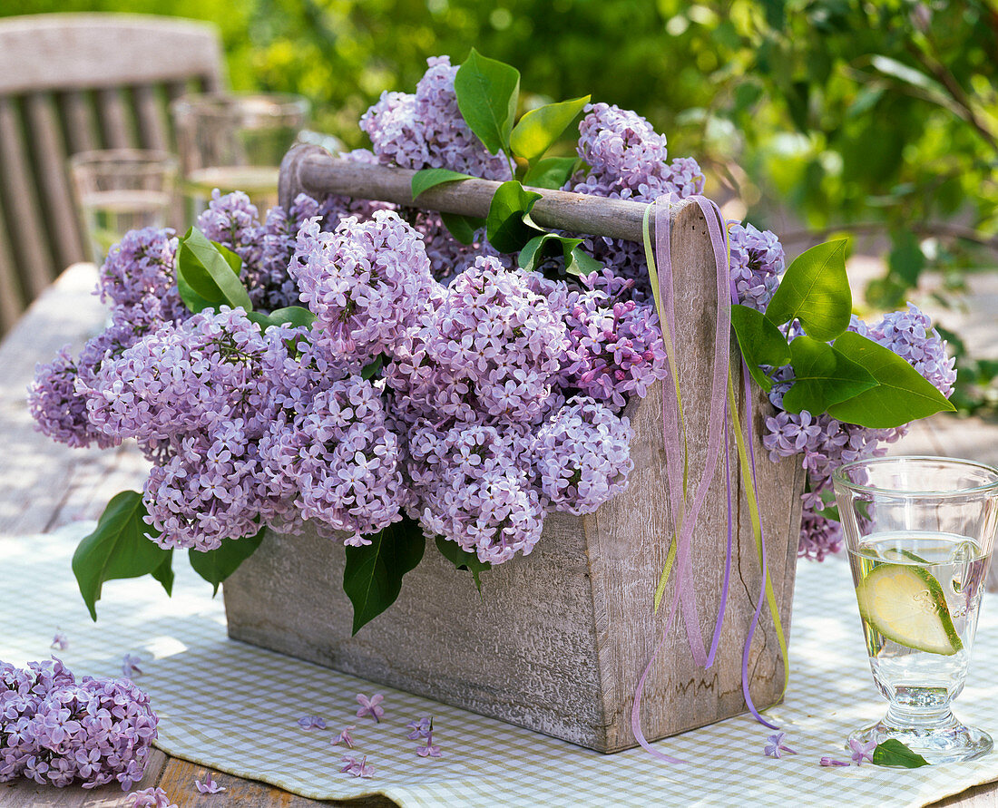 Gesteck aus Syringa (Flieder) in Holzkorb