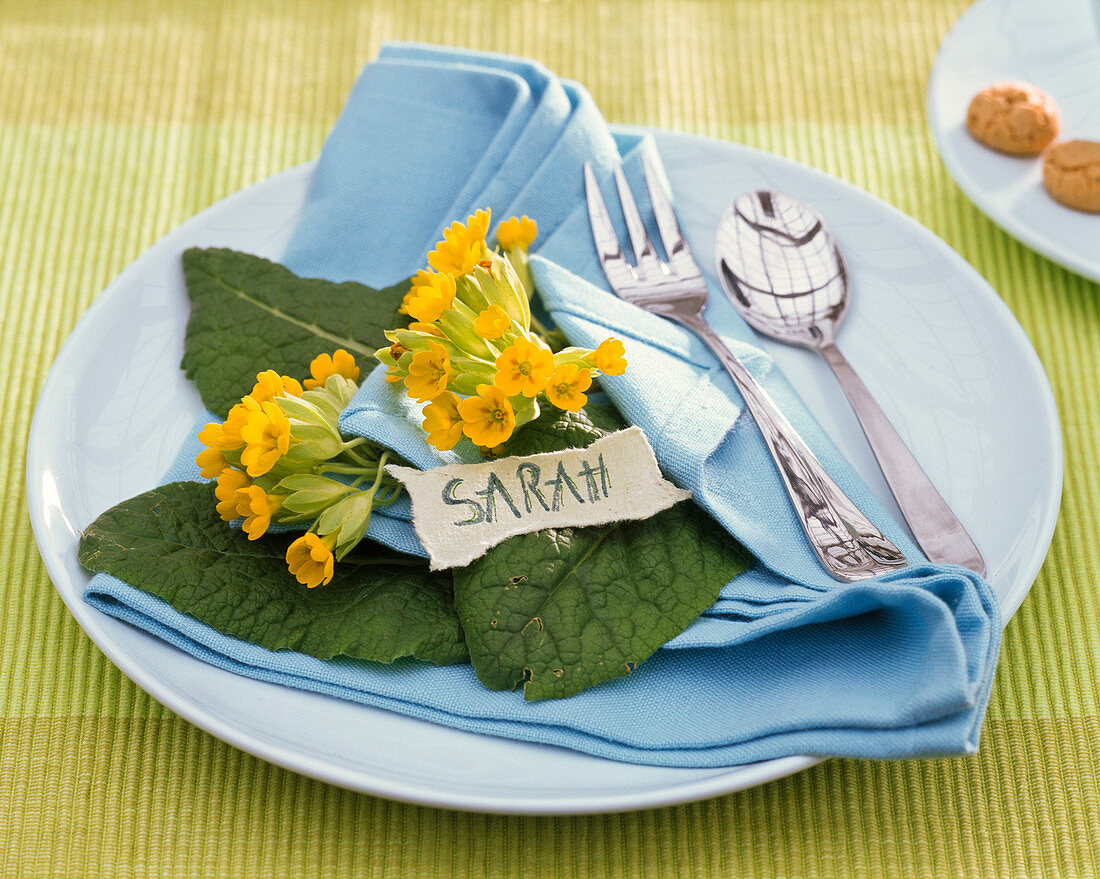 Table decoration with primula veris, blue cloth napkin