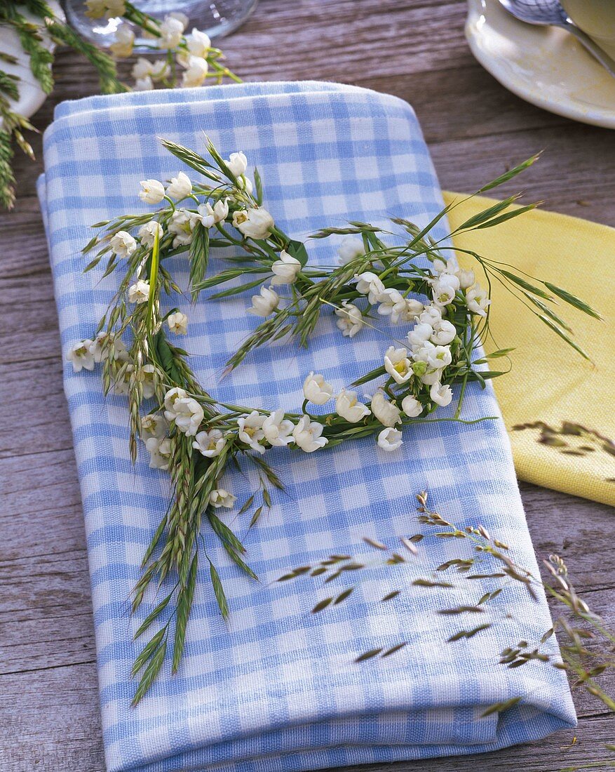 Convallaria and grasses wreath in heart shape on napkin