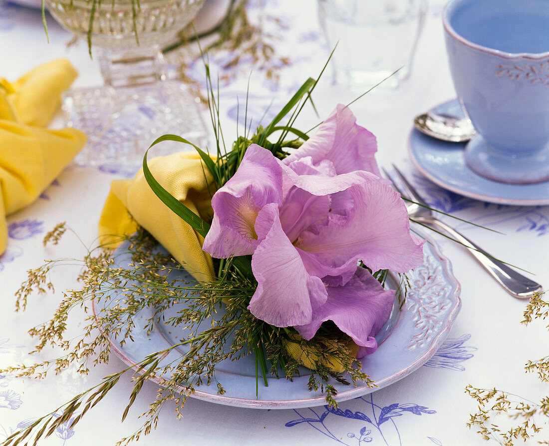 Serviettendekoration mit blauer Iris (Schwertlilien) und Gräsern