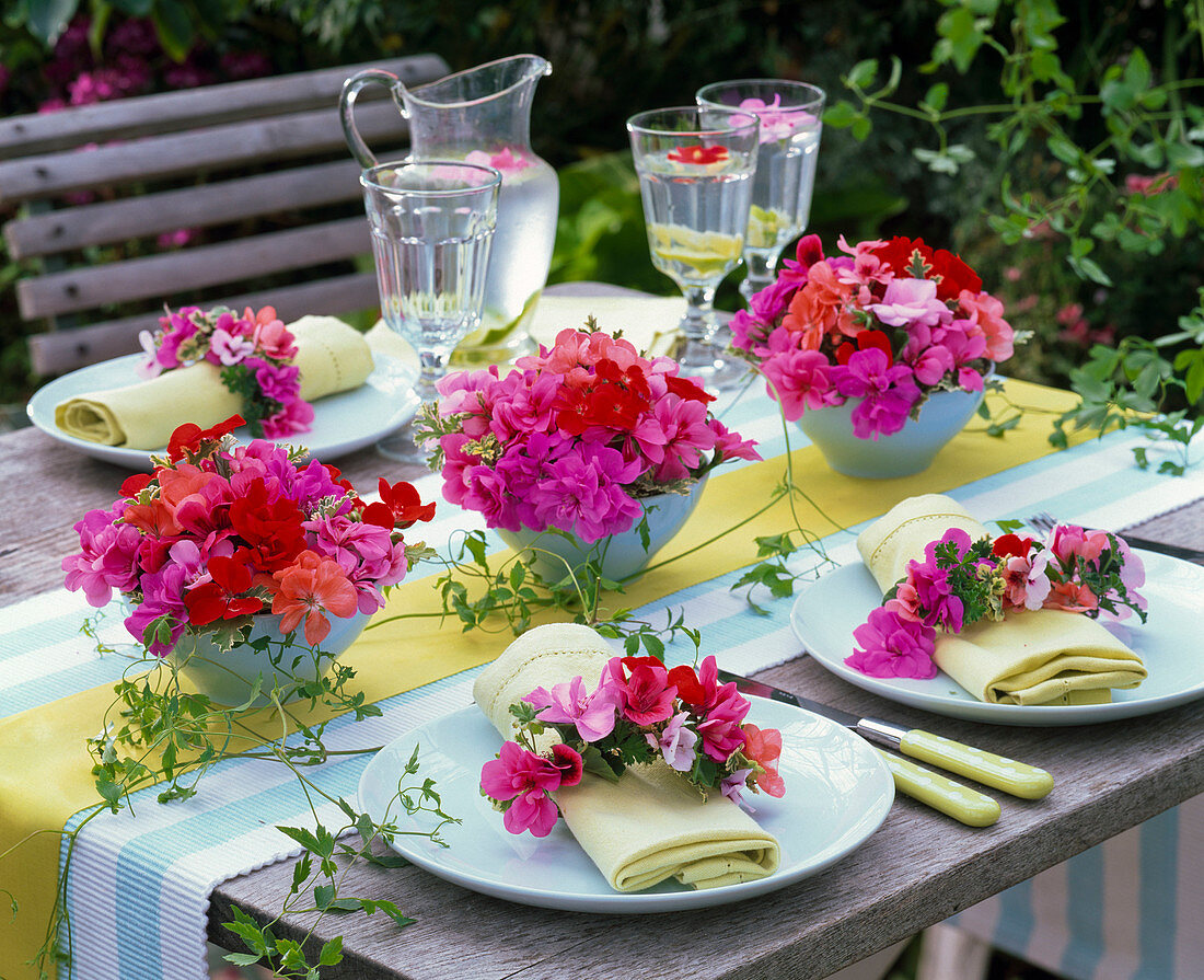 Tischdekoration mit kleinen Gestecken aus Pelargonium (Geranien), Clematis