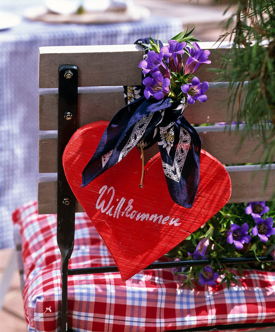 Alpine flair with red wooden heart with scarf and Gentiana scabra