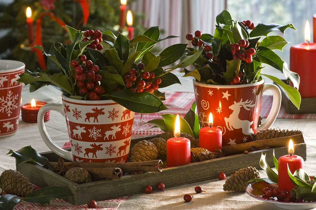 Cups with ilex (holly) on wooden coaster