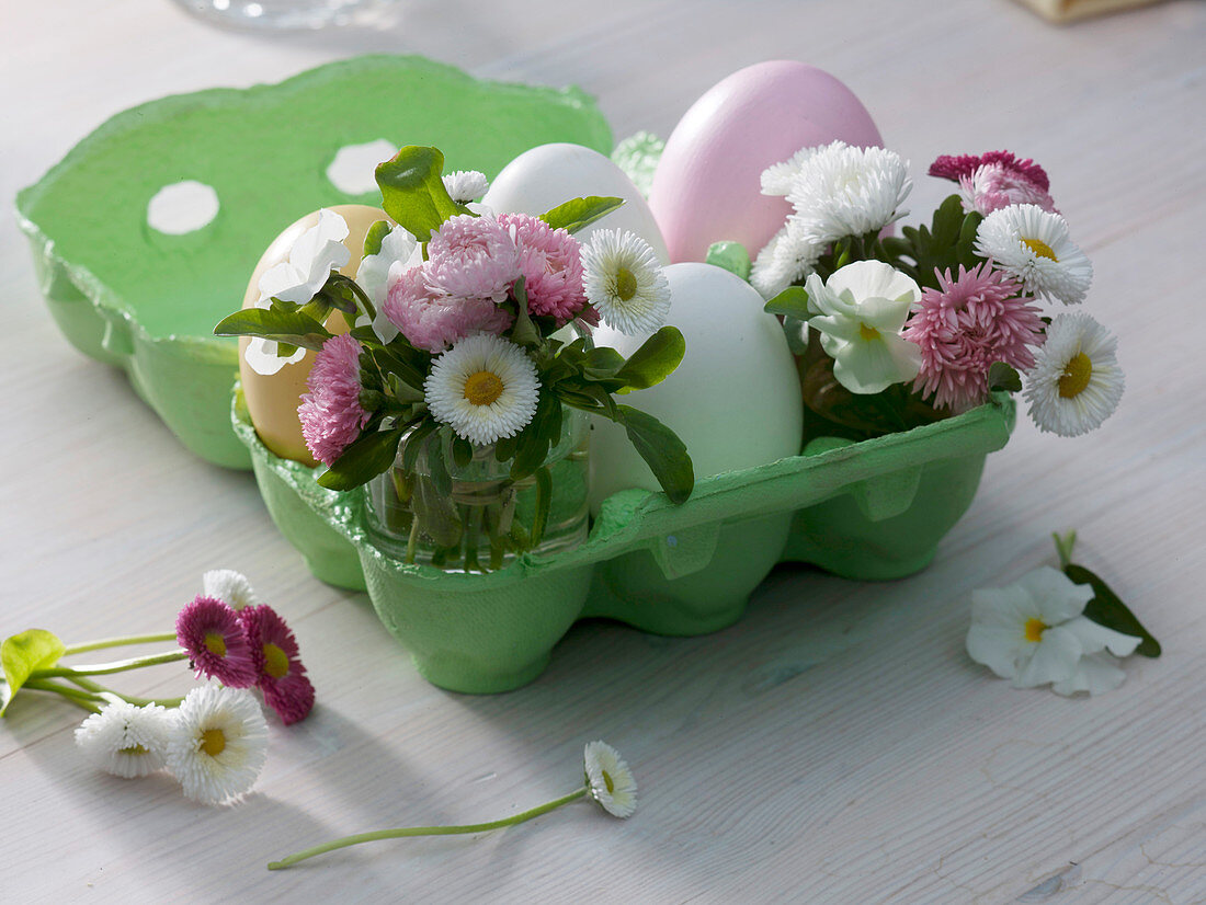 Egg carton with colored and white eggs, small bouquets