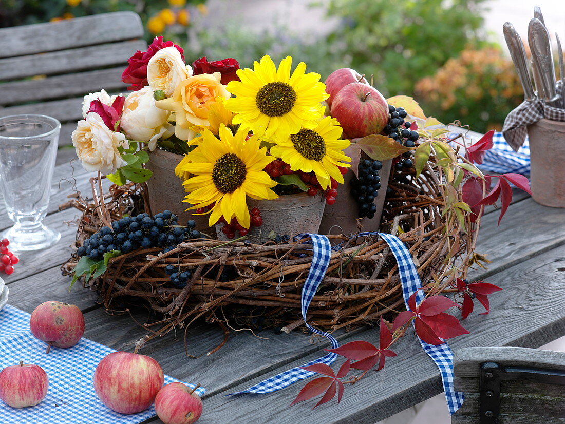 Vine wreath filled with terracotta vases with flowers and fruits