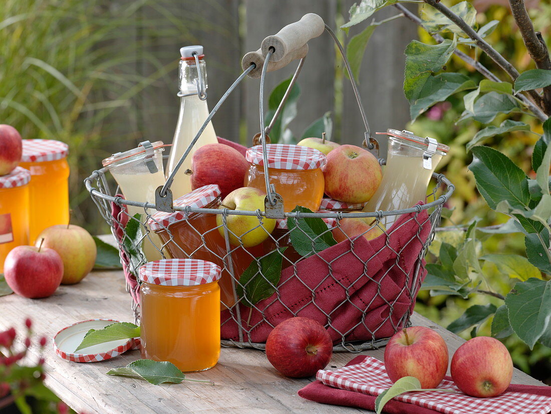 Drahtkorb mit Äpfeln, Apfelgelee und Apfelsaft