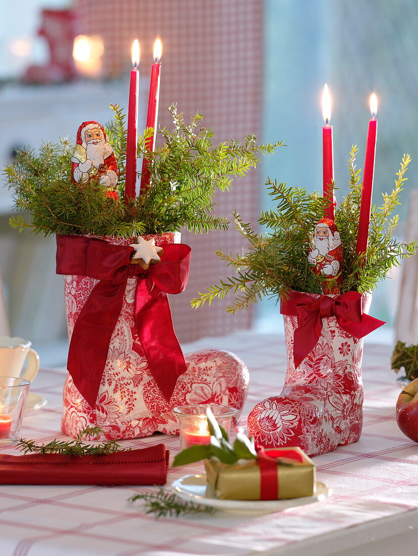 Red and white St. Nikolaus boots with bar candles, red ribbons, branches