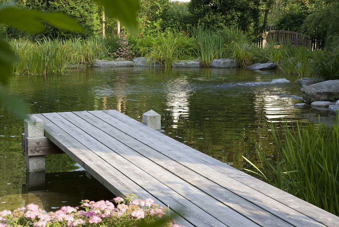 Swimming pond with wooden pier bordered with granite blocks