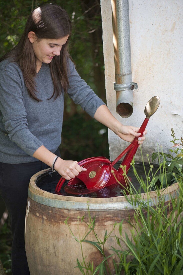 Woman drawing water from water barrel