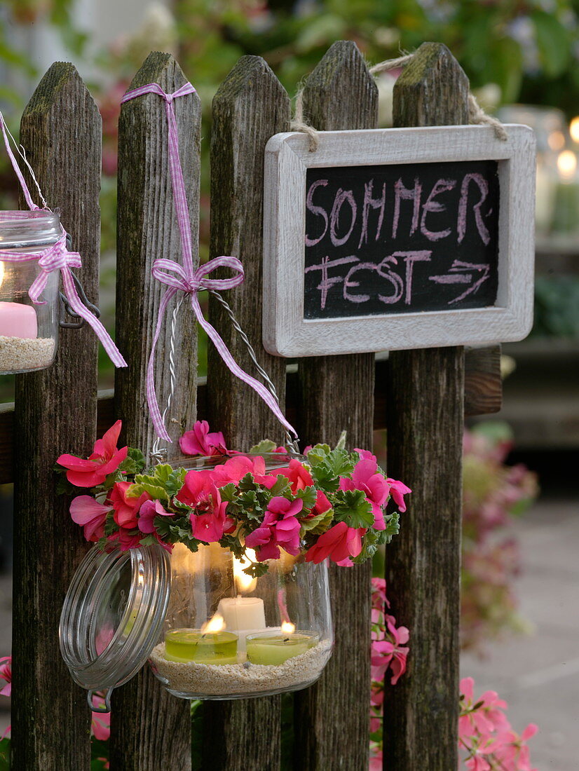 Lidded glasses attached to the fence as lanterns, Pelargonium garland