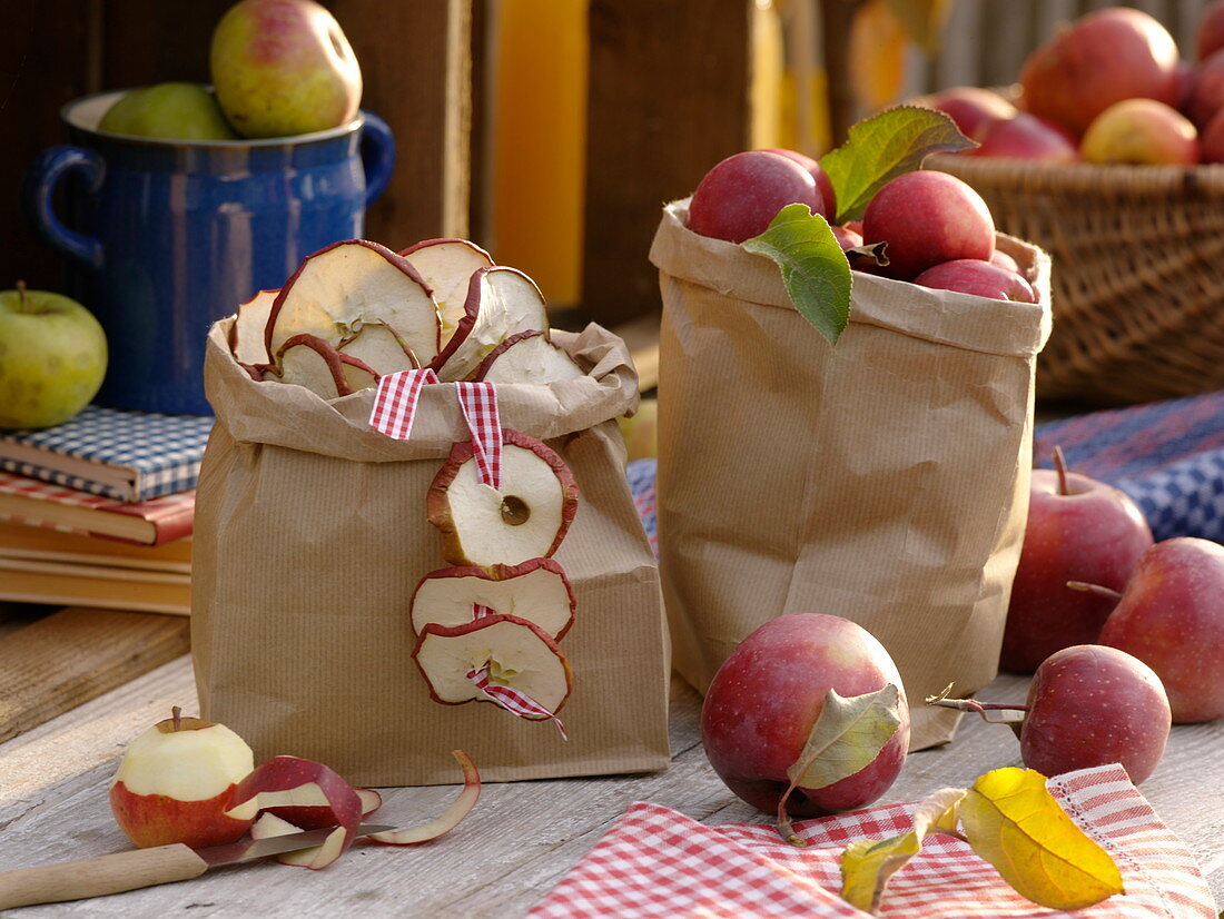 Papiertüten mit Äpfeln und getrockneten Apfelscheiben (Malus)