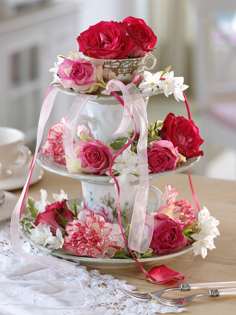 Homemade cake stand made of plates and cups with roses and carnations