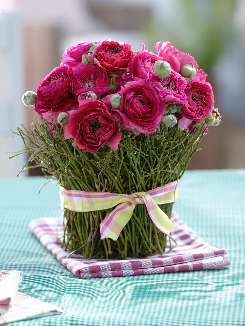 Strauß aus Ranunculus (Ranunkeln), Vase mit Zweigen aus Vaccinium